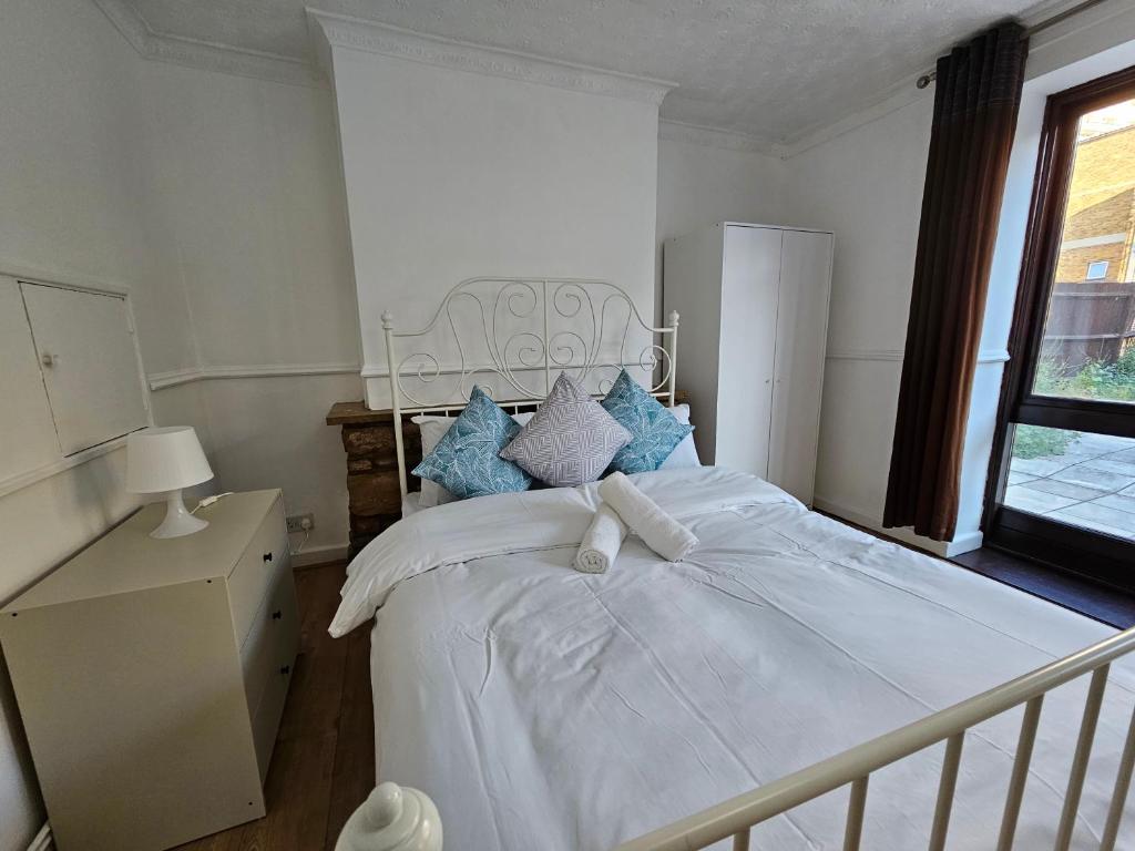 a bedroom with a white bed with blue pillows at London E1 Rooms in London
