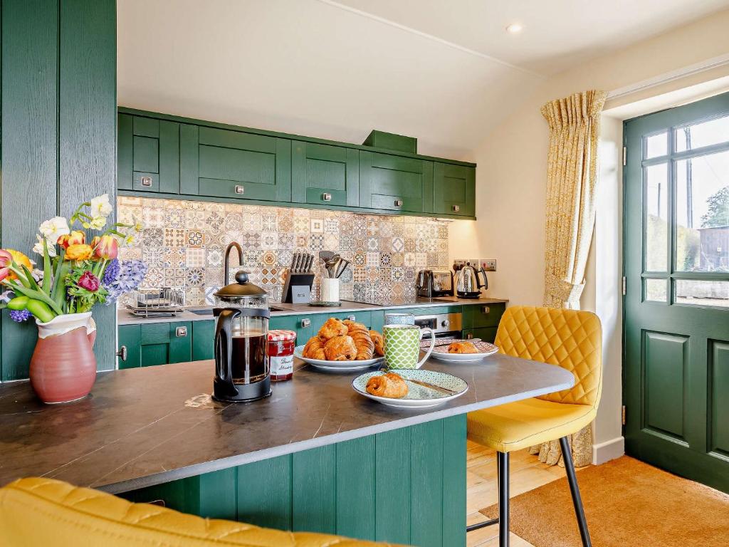 une cuisine avec des armoires vertes et des assiettes de nourriture sur un comptoir dans l'établissement 1 Bed in Sherborne 87292, 