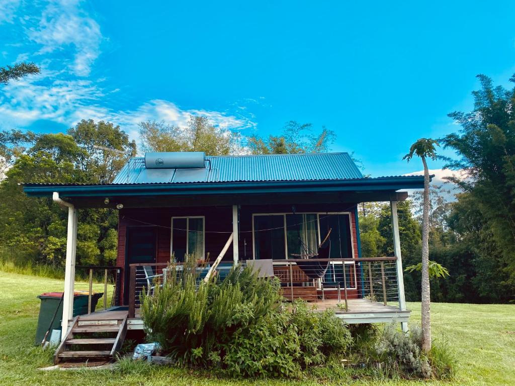 a small house with a green roof on a field at Nimbin waterfall retreat in Nimbin