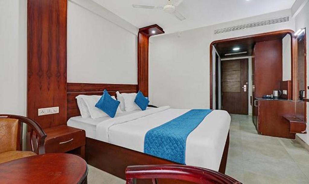 um quarto com uma cama, uma cadeira e uma mesa em FabHotel Majestic South Gate em Trivandrum
