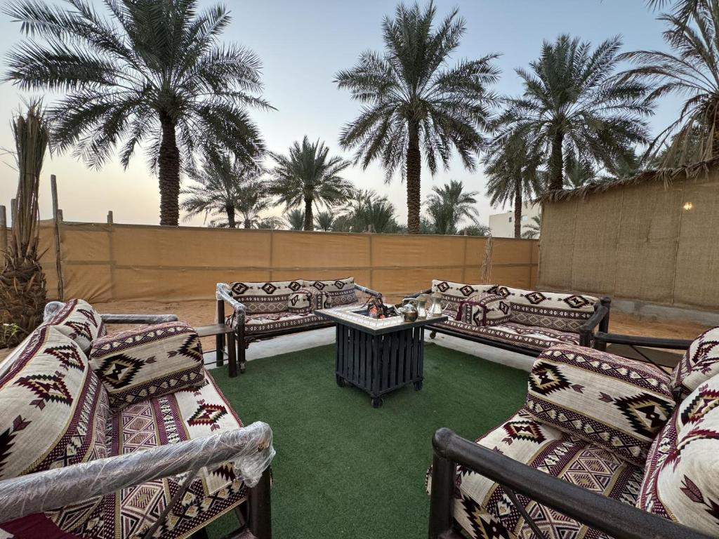 a patio with couches and a table with palm trees at منتجع الرتاج الريفي in Buraydah
