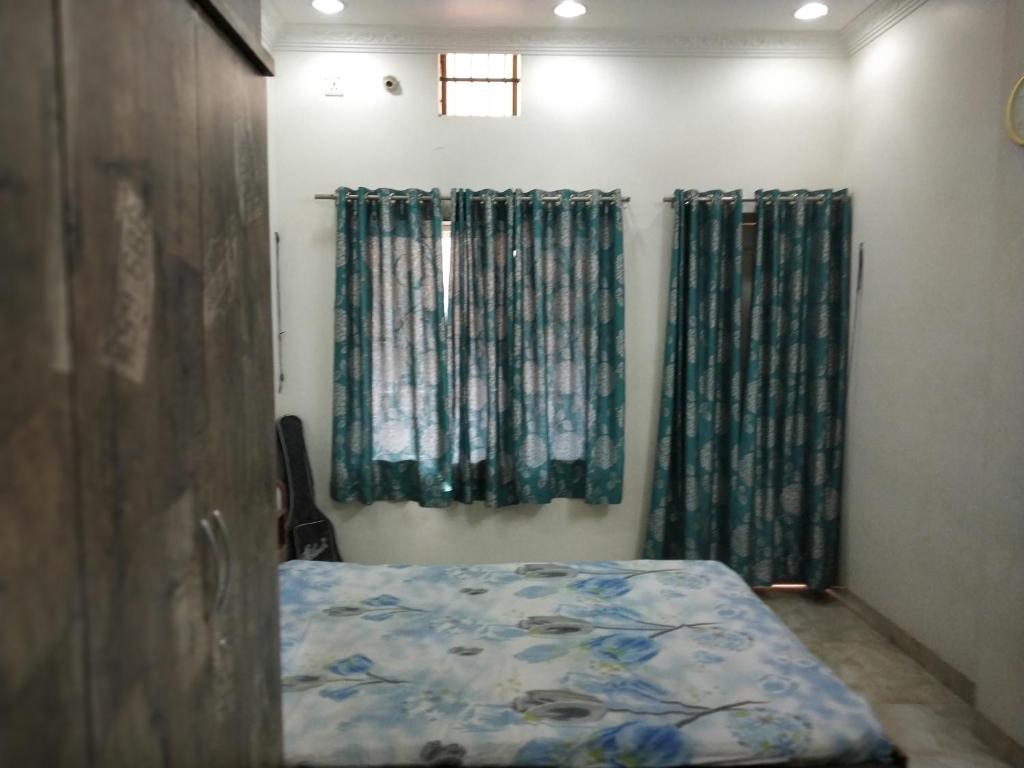 a bedroom with a bed and curtains and a window at Alok Premanand's House in Raipur