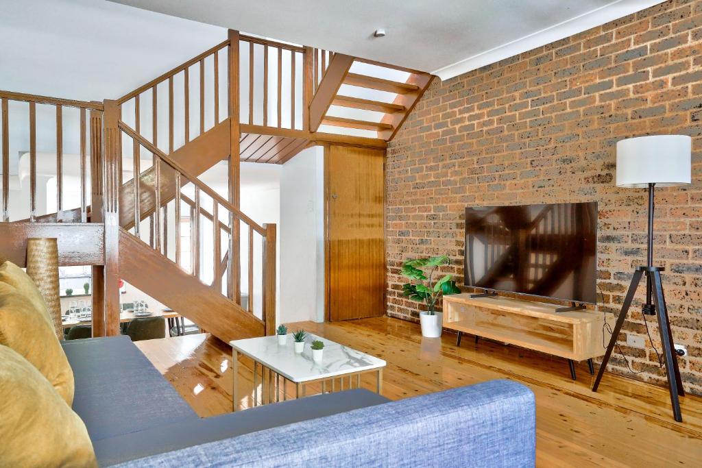 uma sala de estar com um sofá azul e uma parede de tijolos em Elegant House Chippendale - City Center 2 E-Bikes Included em Sidney
