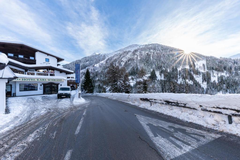 una strada innevata con un edificio e una montagna di Hotel Karl Schranz a Sankt Anton am Arlberg