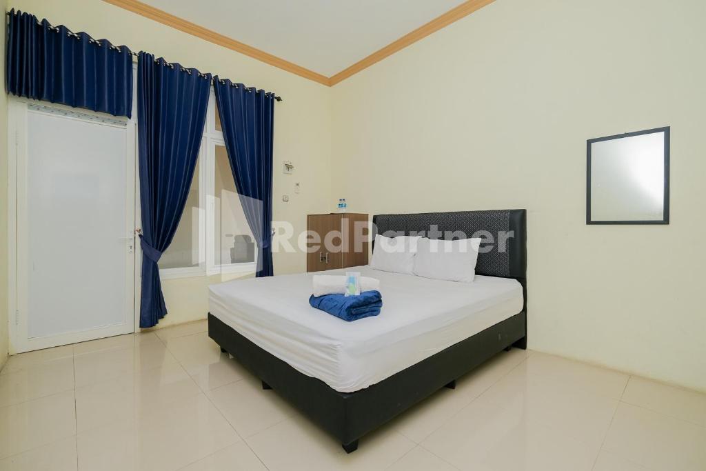 Schlafzimmer mit einem großen Bett und blauen Vorhängen in der Unterkunft Grand Kencana Guesthouse near Wisata Bahari Lamongan Mitra RedDoorz in Paciran