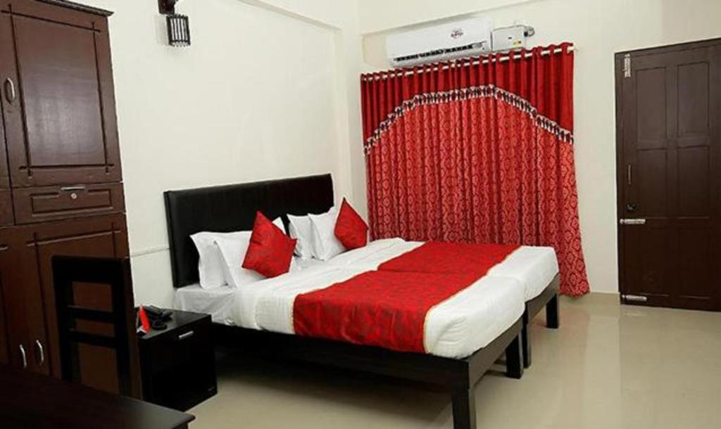 FabExpress Majestic Le Frank في Kazhakuttam: غرفة نوم بسرير وستارة حمراء