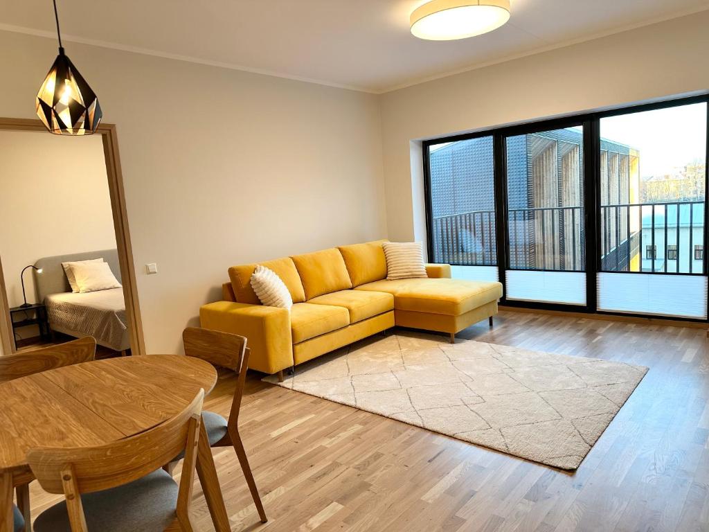 ein Wohnzimmer mit einem gelben Sofa und einem Tisch in der Unterkunft Riia 22 Apartment in Tartu
