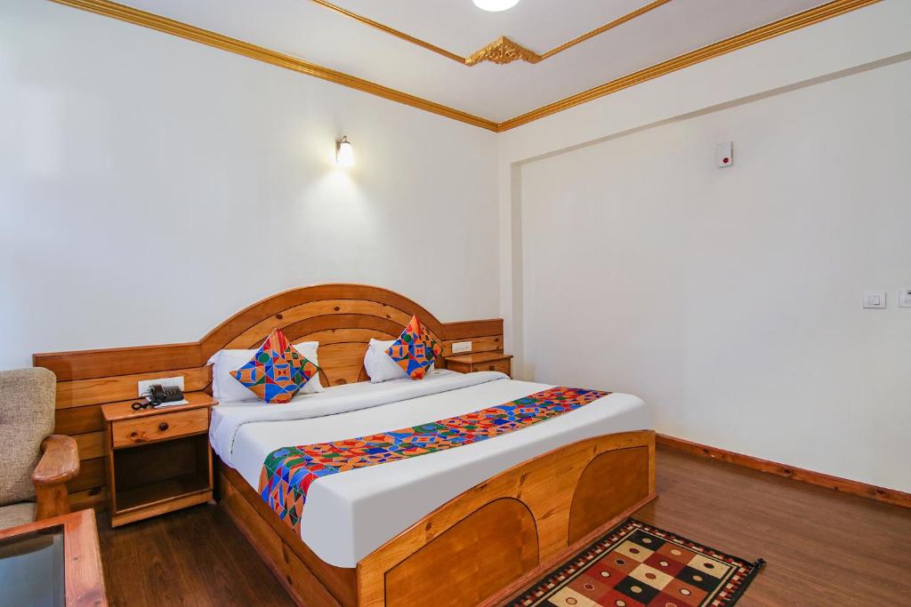 a bedroom with a bed with a wooden headboard at FabHotel Prini Inn in Manāli