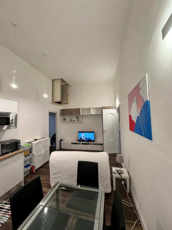 ナポリにあるRiviera Apartment Napoliの白いベッドとキッチンが備わる小さな客室です。