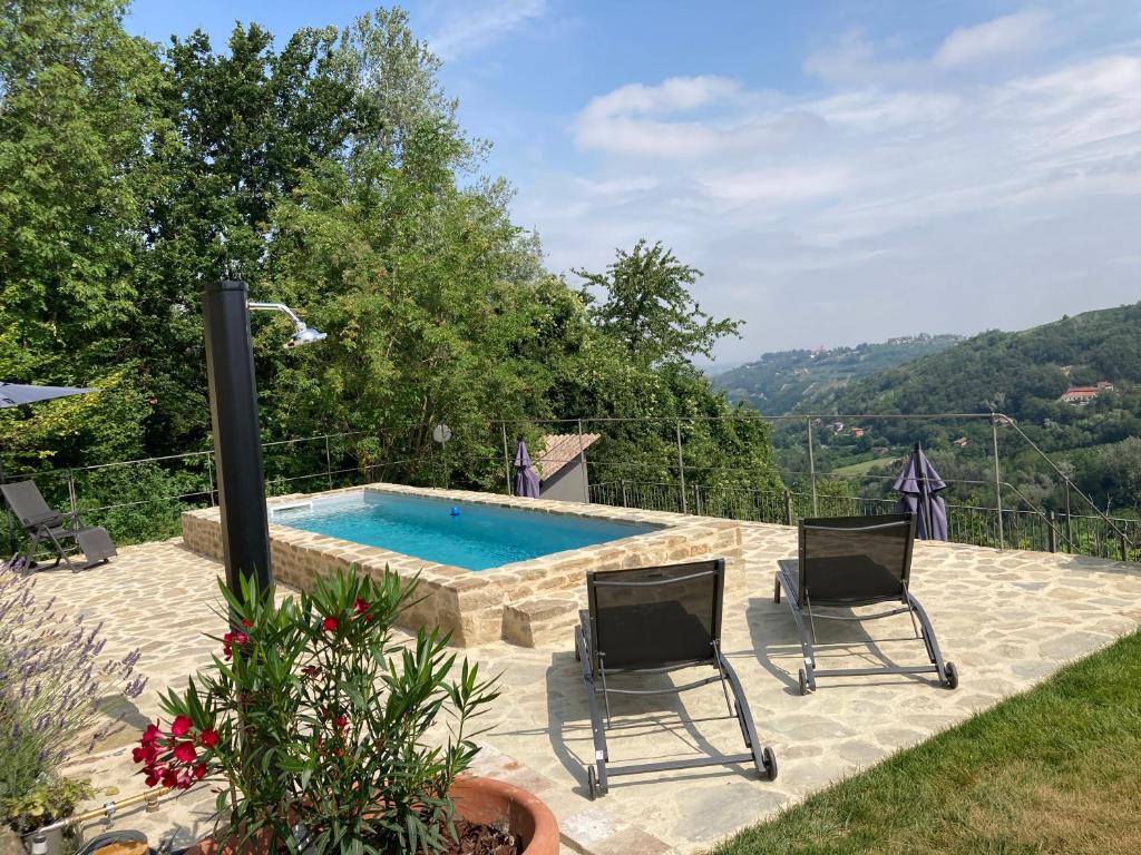 eine Terrasse mit 2 Stühlen und einem Pool in der Unterkunft Villa Menaluna - 4-bedroom secluded country house with pool in Rocchetta Palafea