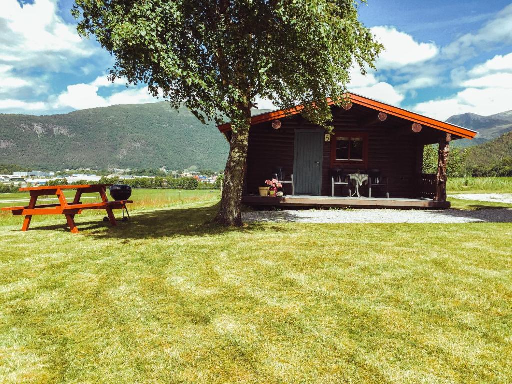 a log cabin with a picnic table and a tree at Åndalsnes Hytteutleie in Åndalsnes