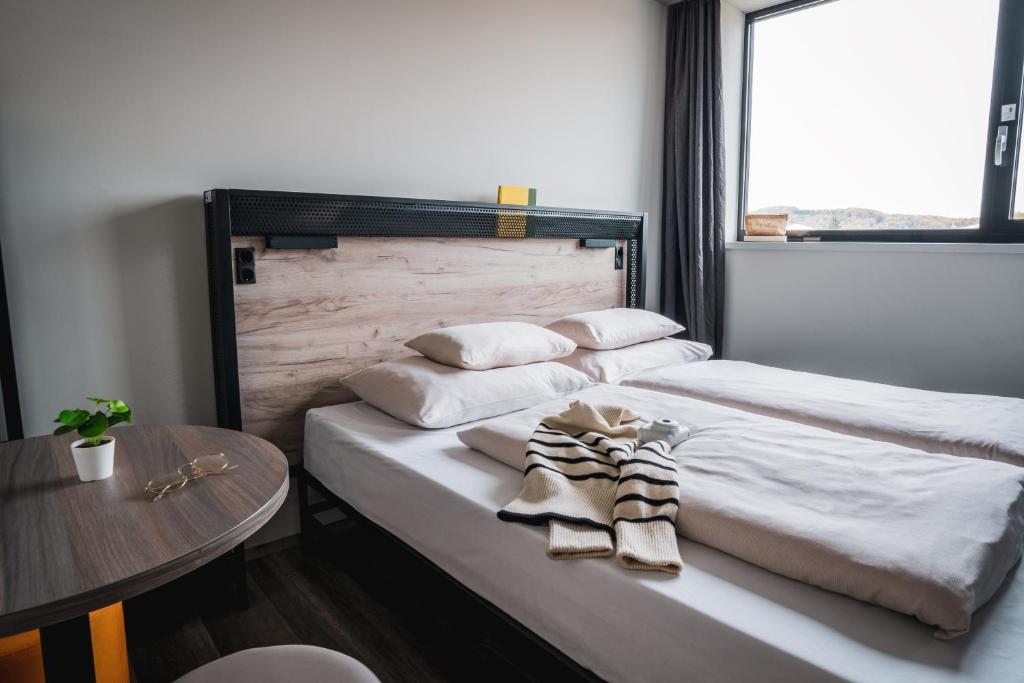 uma cama com duas almofadas e uma mesa num quarto em harry's XL Hotel em Salzburgo
