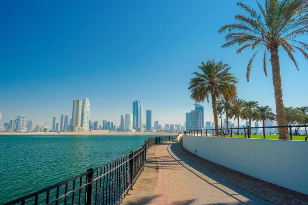 Studio Luxury Apartment by Mamzar Beach في دبي: ممشى بجانب تجمع الماء بالنخيل