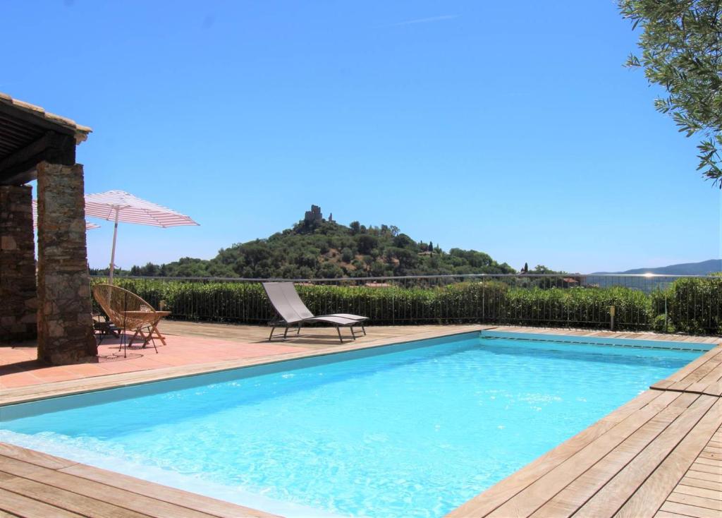 a swimming pool with a table and chairs next to a house at Villa Tara 6 chambres piscine privée vue panoramique sur les collines de Grimaud in Grimaud