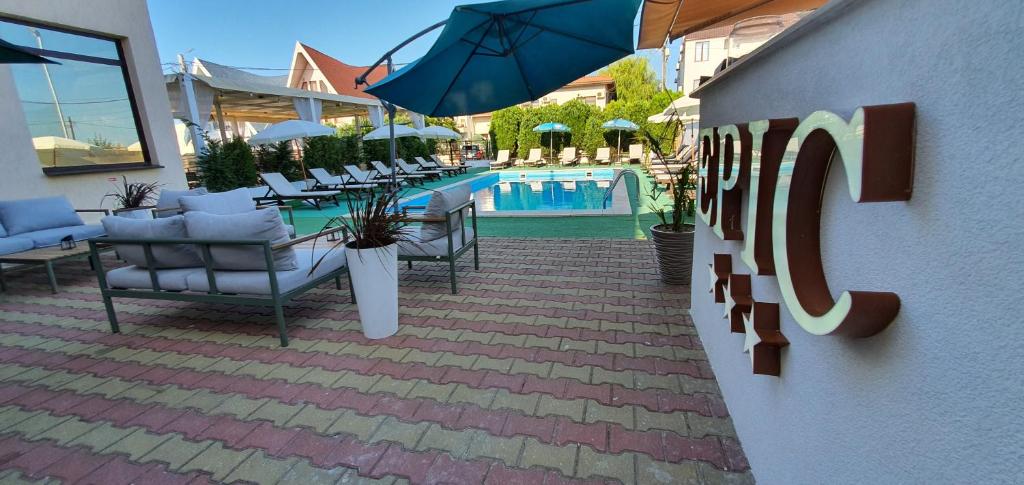 a patio with chairs and an umbrella next to a pool at Vila EPIC in Costinesti