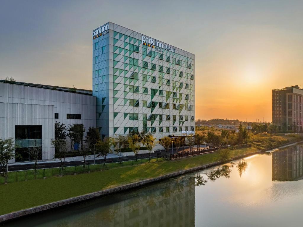 QingpuにあるPark Inn by Radisson Shanghai Shanghai Middle Jiasong Road Outletsの夕日の川の横の建物