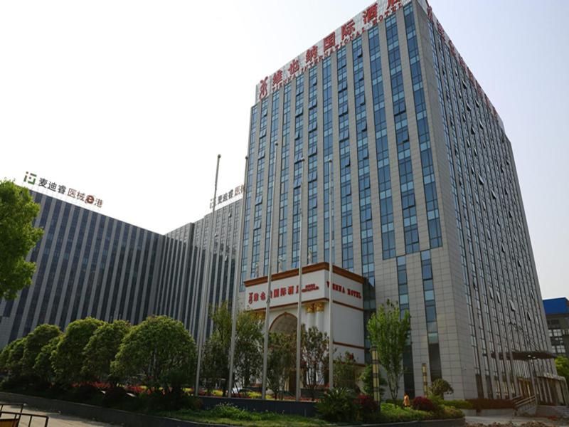 een groot gebouw met een bord ervoor bij Vienna International Hotel Shanghai Hongqiao Airport Convention and Exhibition Center Huaxu Highway in Qingpu