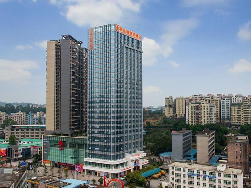 um edifício de vidro alto numa cidade com edifícios em Vienna International Hotel Shenzhen Xiashuijing Metro Station em Shenzhen