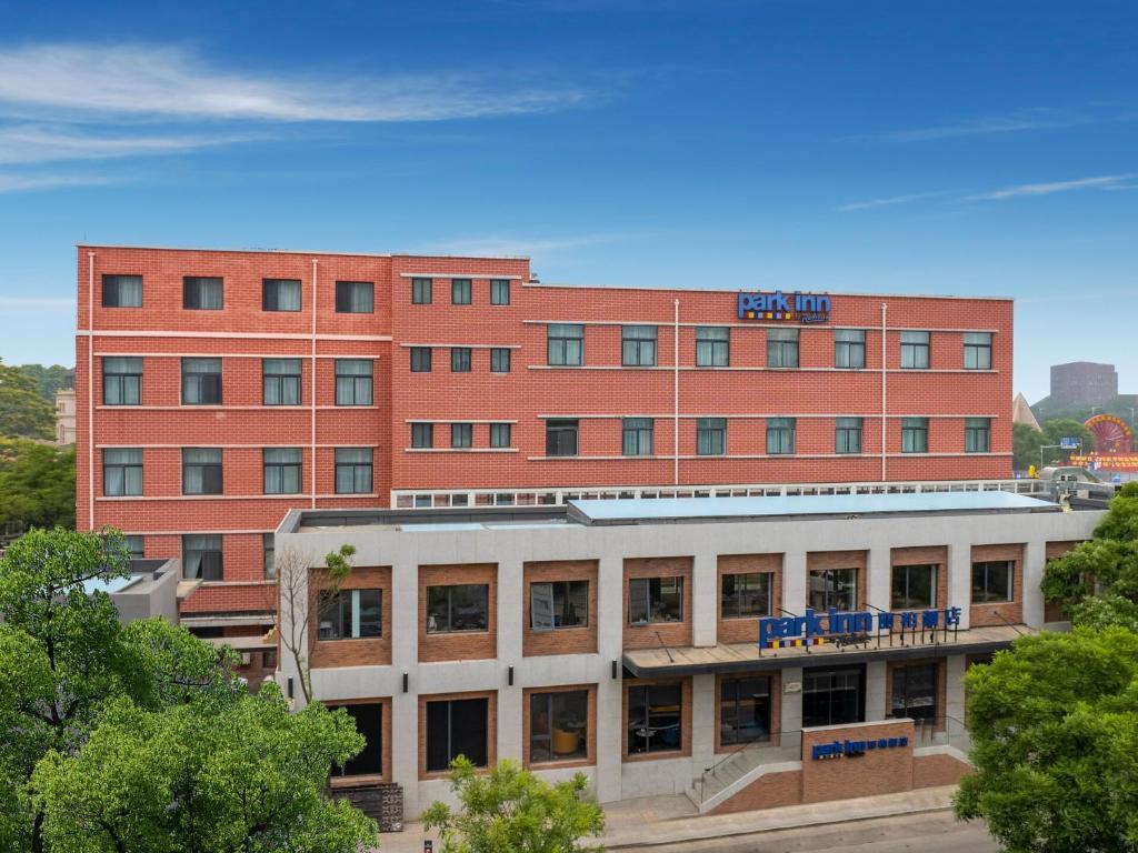 a large red brick building with a hotel at Park Inn by Radisson Tianjin Five Old Street Nanjing Road in Tianjin