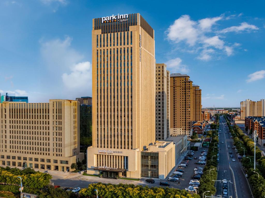 een hoog gebouw met een hotelbord erop bij Park Inn by Radisson Tianjin Jinghai Wanda Plaza in Jinghai