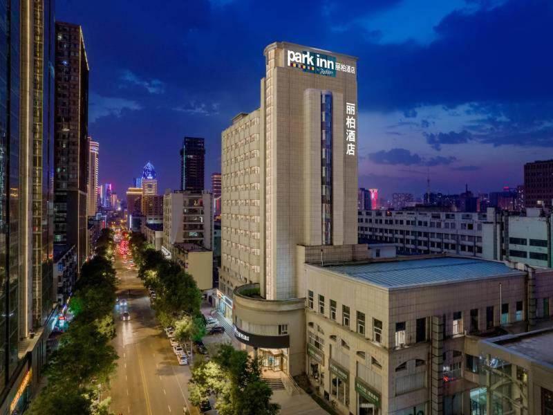 un edificio alto con un cartel en una ciudad en Park Inn by Radisson Taiyuan Railway Station Hotel en Taiyuán