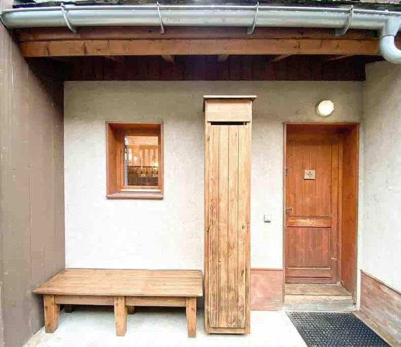 a wooden bench in front of a building with a door at Chalet Mélèze skis aux pieds Alpes, Sainte-Foy station 1550 in Sainte-Foy-Tarentaise