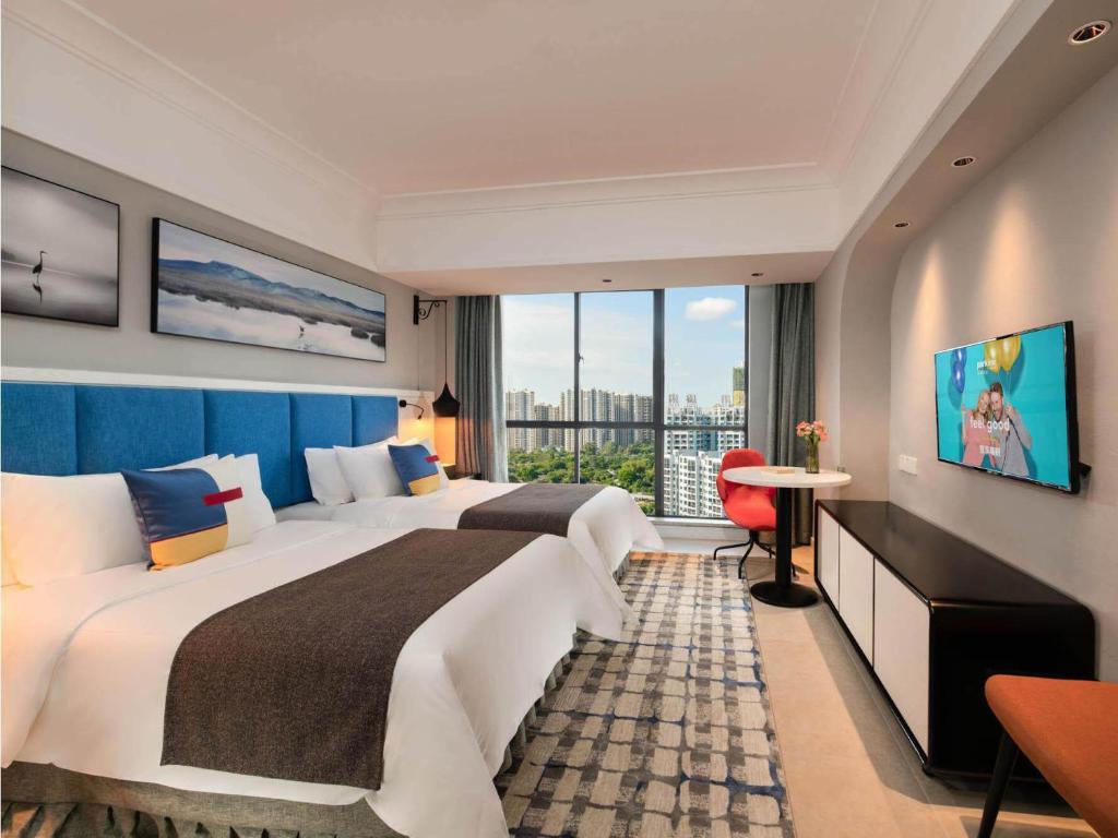 北海市にあるPark Inn by Radisson Beihai Silver Beach Wanda Plazaの大きなベッドと窓が備わるホテルルームです。