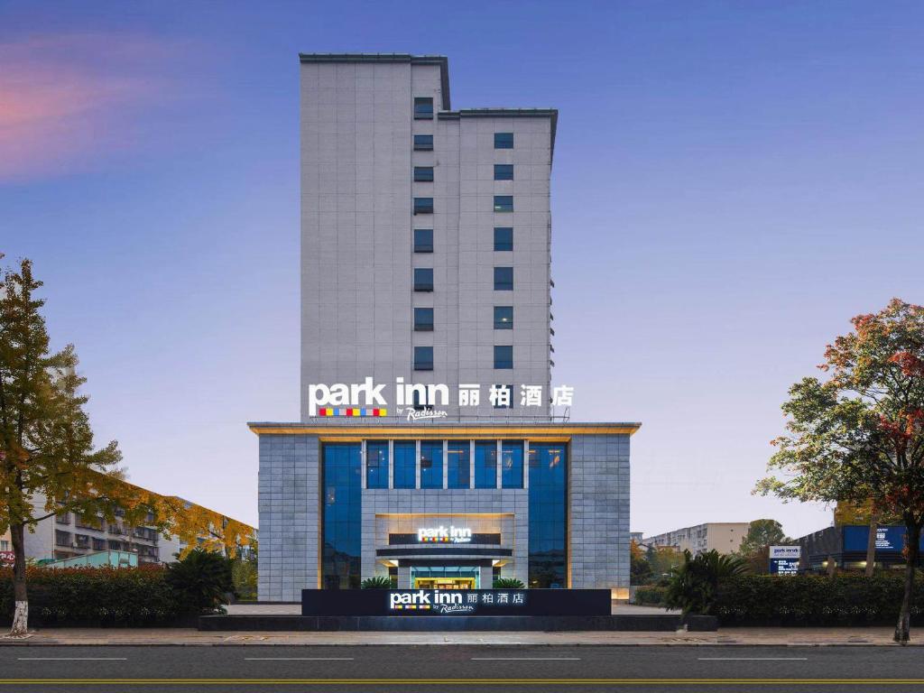 a building with a sign on top of it at Park Inn by Radisson Hanzhong Central Square & High speed rail station in Hanzhong