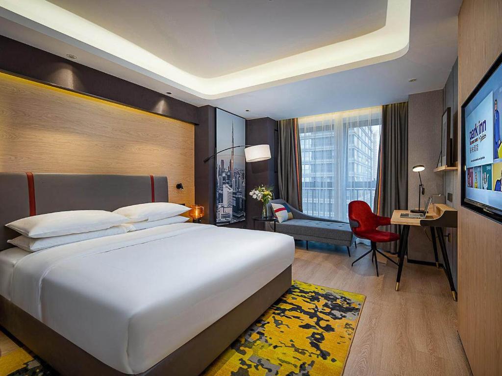 Cette chambre comprend un grand lit et un bureau. dans l'établissement Park Inn by Radisson Chongqing Yuelai International Expo Center, à Chongqing