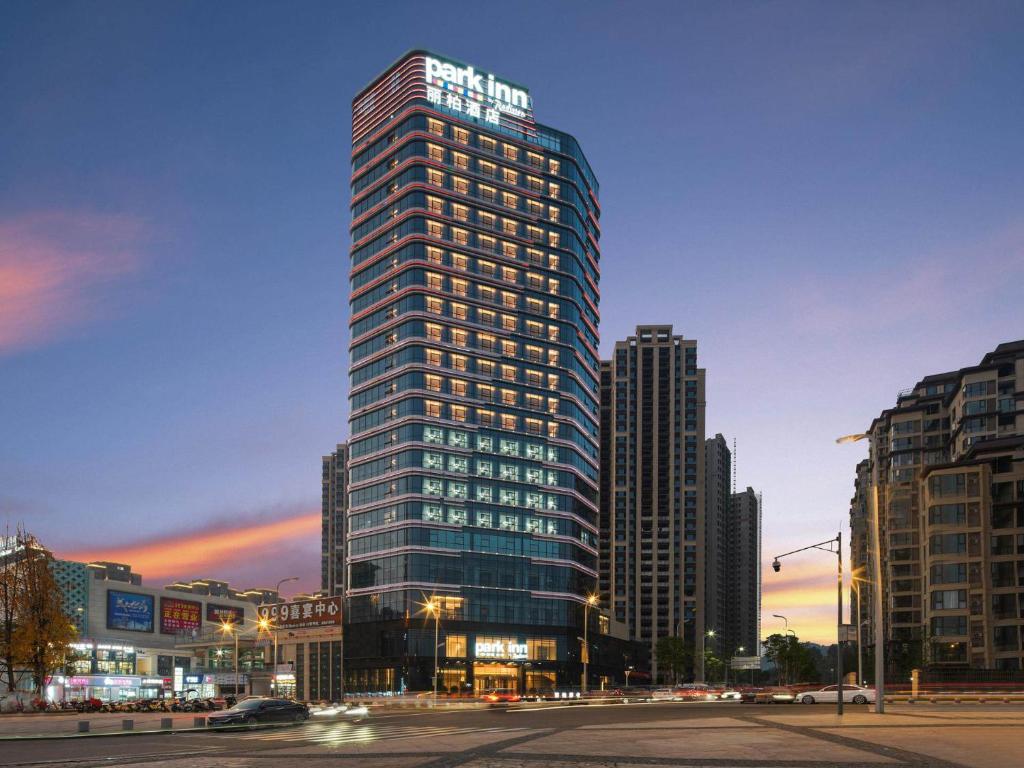 a tall building in a city at night at Park Inn by Radisson Nanchong Yilong Star City Plaza in Yilong