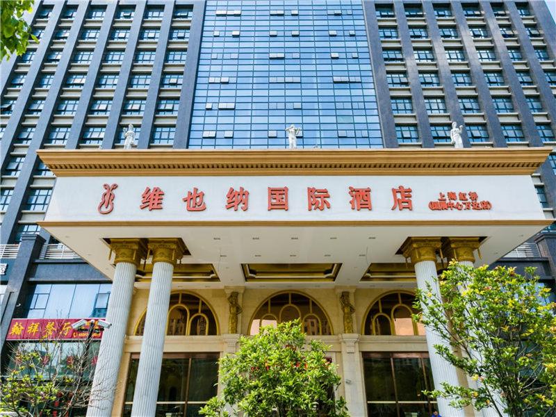 a building with a sign in front of a tall building at Vienna International Hotel Shanghai Hongqiao International Exhibition Center Aite Road in Jiading