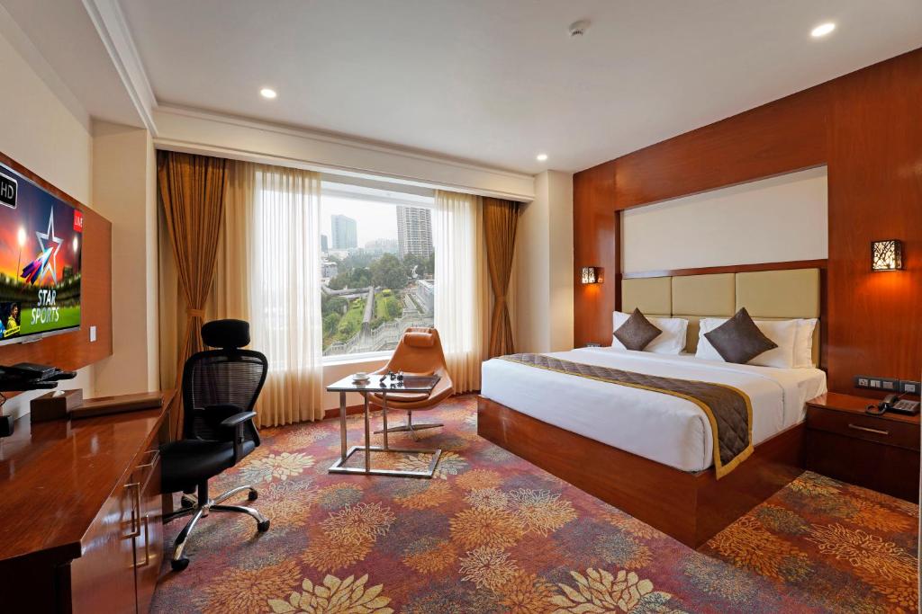 バンガロールにあるKINGSTON HOTELのベッドとテレビが備わるホテルルームです。