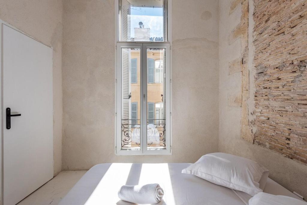 a white bedroom with a bed and a window at |Aaa|- Pure &amp; Natural Massilia City Center in Marseille
