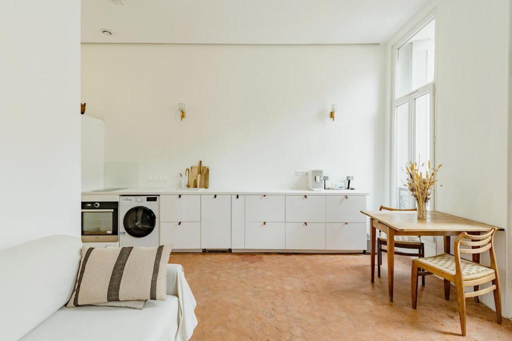 a white living room with a table and a kitchen at |Aaa|- Pure &amp; Natural Massilia City Center in Marseille