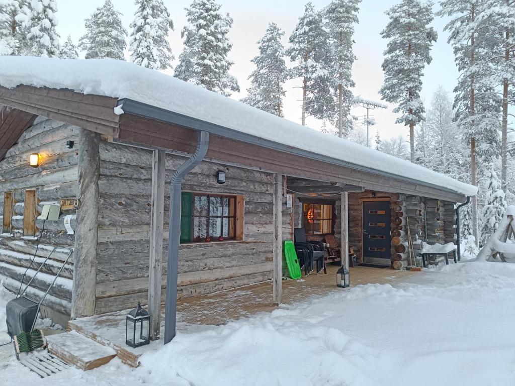 Cabaña de madera con nieve en el techo en Mäntyharju-mökki, en Syöte