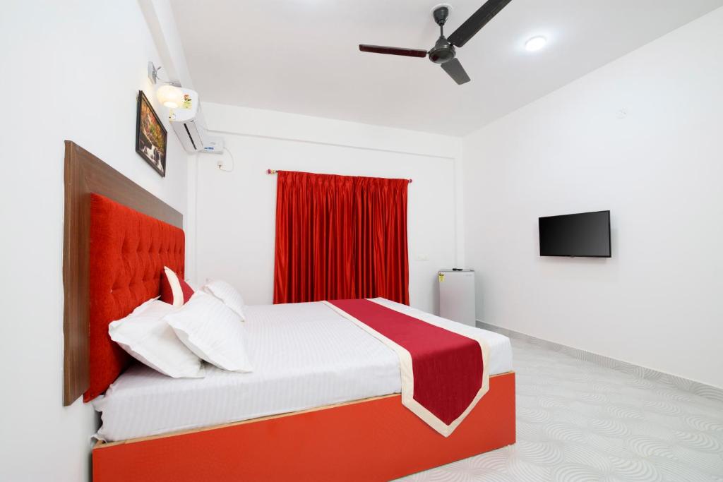 a bedroom with a red and white bed and a tv at 14 Door Home Stay in Calangute