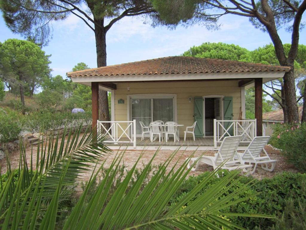 una pequeña casa amarilla con sillas y patio en GASMED41 Golfe de Saint-Tropez - Chalet californien 3 chambres pour 8 personnes en Gassin