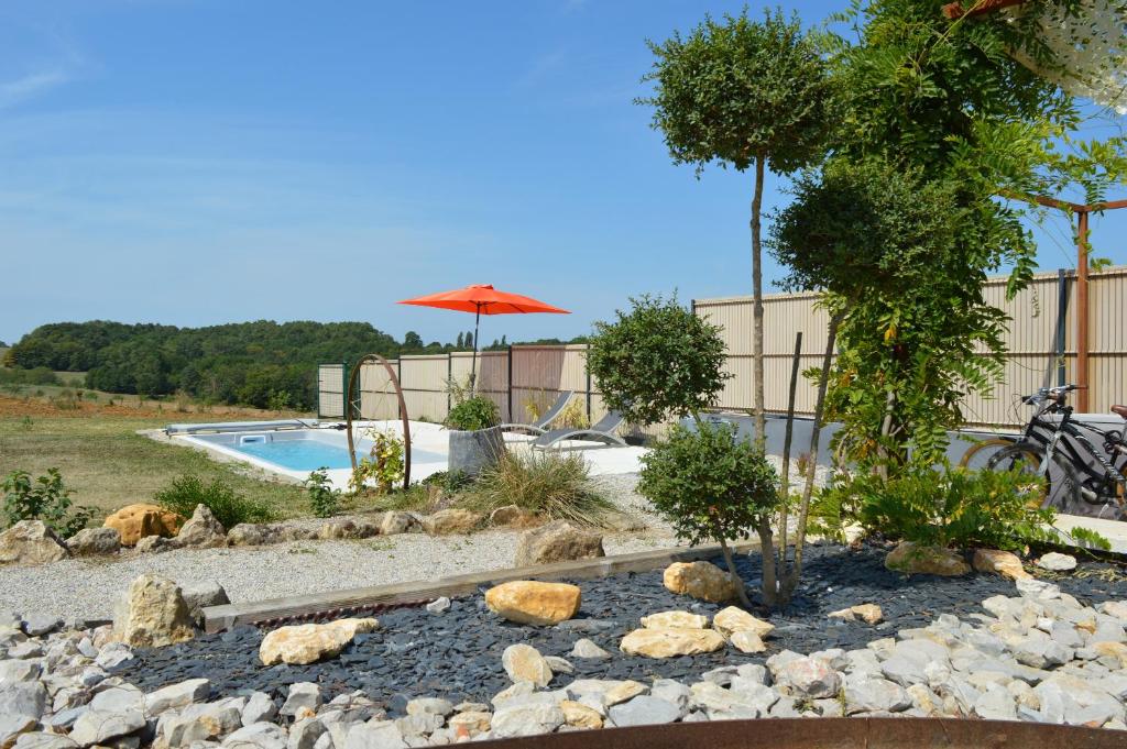 a rock garden with a swimming pool and an umbrella at Le Séchoir un Grand coin de paradis in Saint-Amand-de-Coly