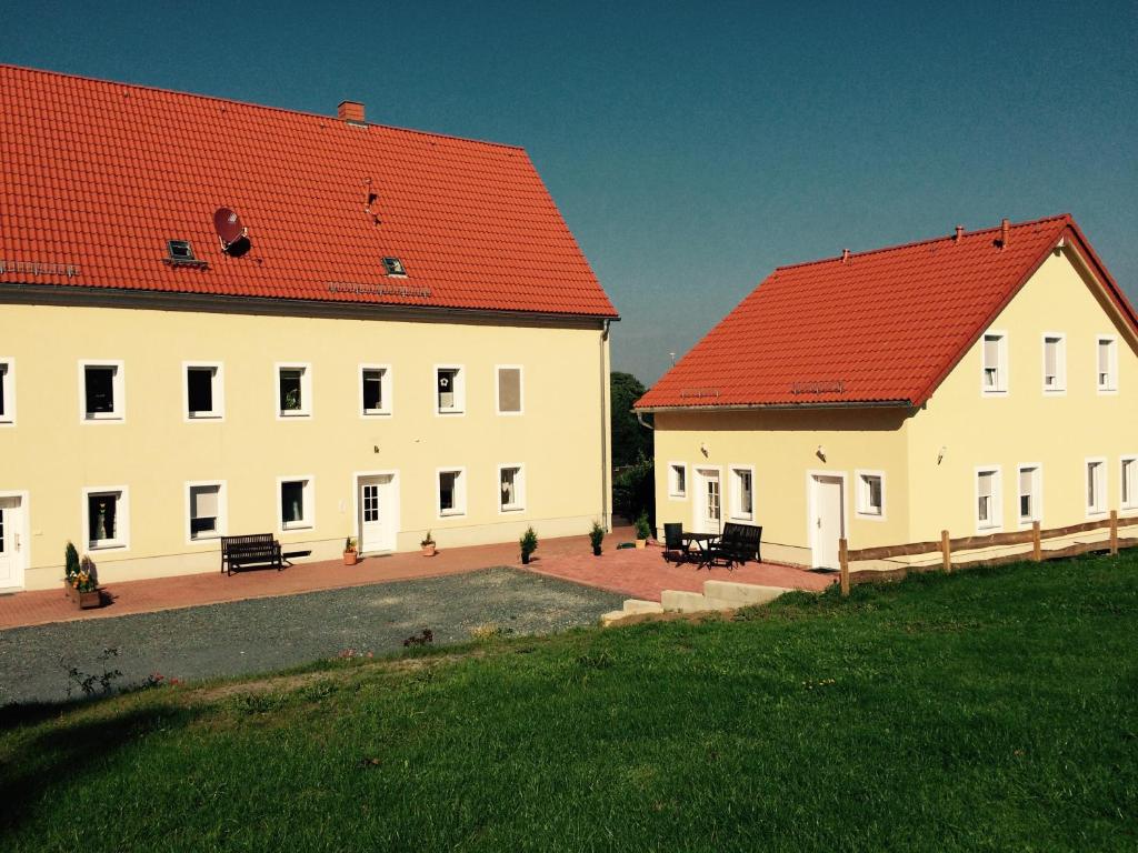 twee witte gebouwen met rode daken in een veld bij Landhaus Böhmer, Ferienhaus Schrammsteinblick in Kurort Gohrisch