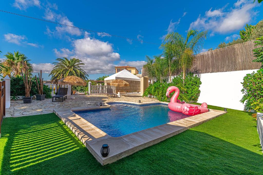 uma piscina com um flamingo insuflável cor-de-rosa num quintal em Villa Aurora with Heated Pool em La Cisnera