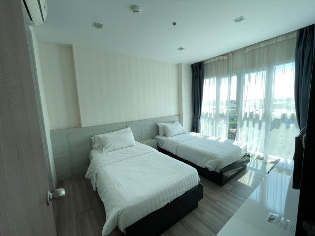 Habitación de hotel con 2 camas y ventana en The One Prio Residence, en Chiang Mai