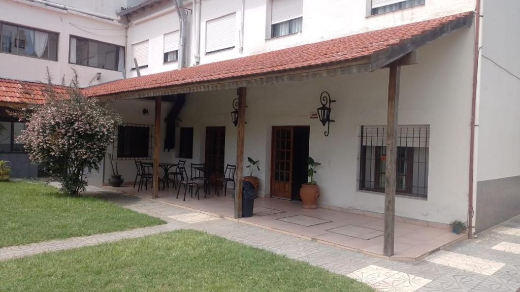 una casa bianca con patio arredato con tavoli e sedie di Eluney Hotel a San Clemente del Tuyú