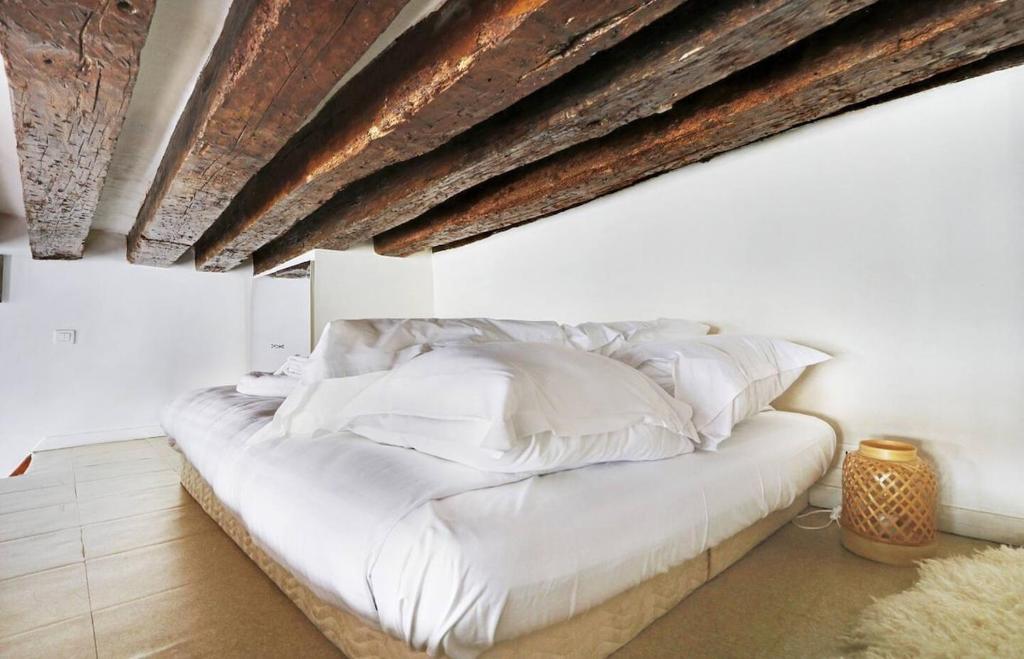 un lit avec des draps blancs et des oreillers dans une chambre dans l'établissement Paris Marais Ville de VERRE77, à Paris