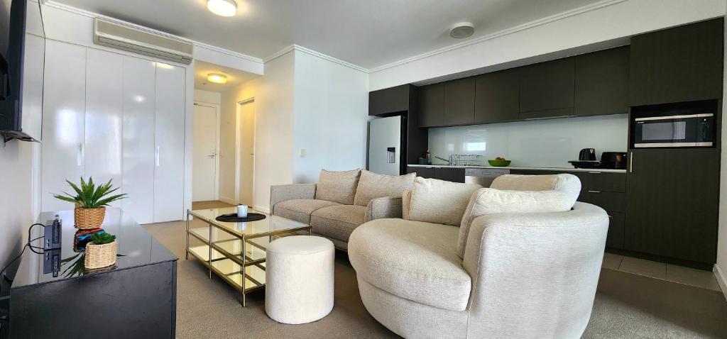 a living room with a white couch and a kitchen at Room in shared apartment in Fortitude Valley in Brisbane