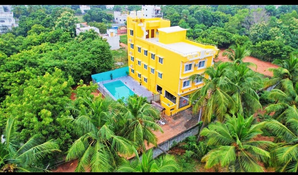einen Blick über ein gelbes Haus mit Pool in der Unterkunft Auro Galaxy Pondy with Swimming Pool in Kottakupam