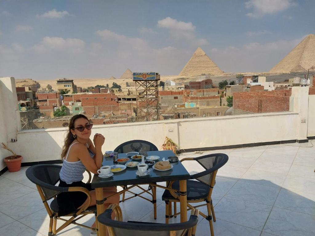 Zoser Pyramids View- Foreiigners only في القاهرة: امرأة تجلس على طاولة أمام الاهرامات