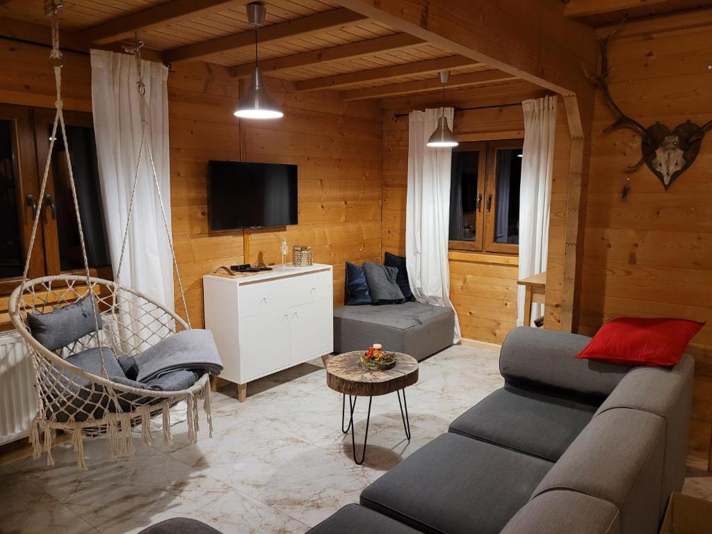 ein Wohnzimmer mit einem Sofa und einem TV in der Unterkunft Dom Nad Stawem Dłużec 55A in Mrągowo