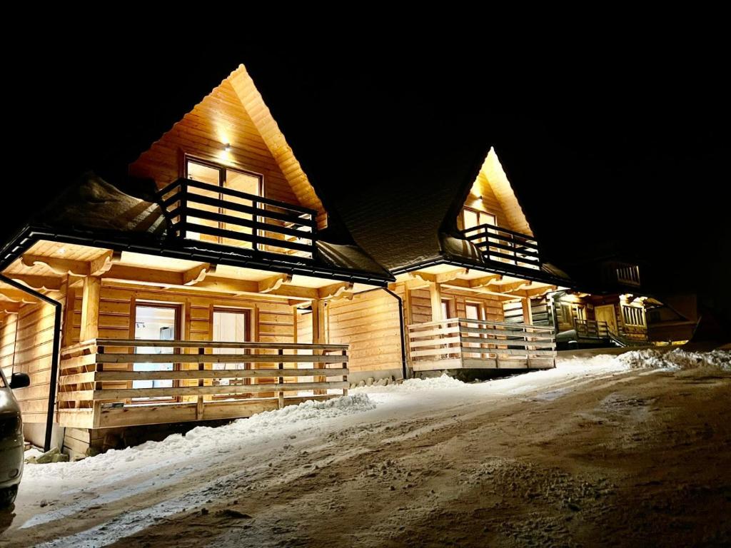 a group of log homes in the snow at night at Domek na Szlaku koło ZAKOPANEGO in Bańska Niżna