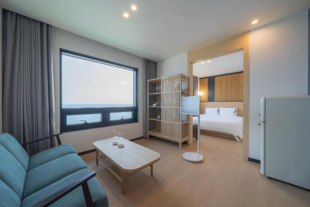 um quarto com um sofá, uma cama e um frigorífico em Hotel 701 Gyeongju em Gyeongju