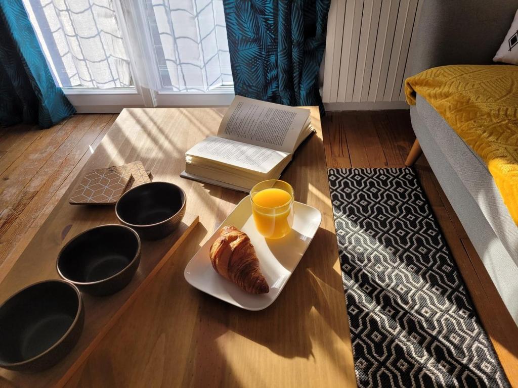 a coffee table with a plate of food and a cup of orange juice at La Compiègnoise - Spacieux - Lumineux - Cosy in Compiègne